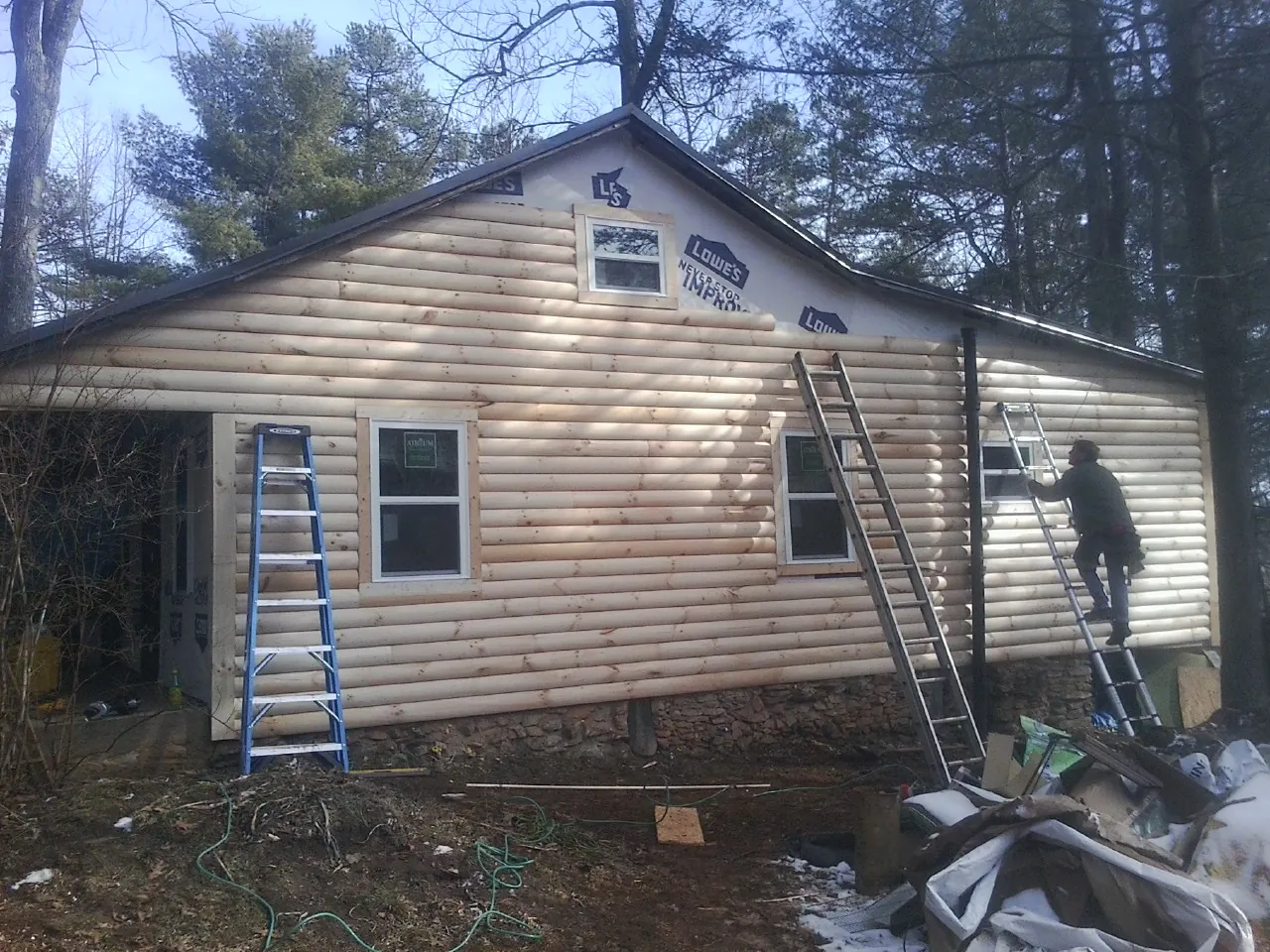 Ladders set against fresh log siding during an exterior remodel in Sangerfield