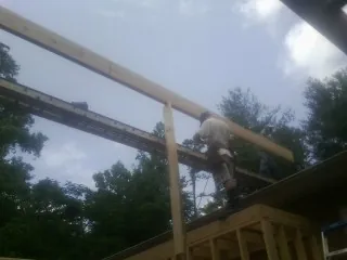 Carpenter setting a ridge beam over a new addition frame — Ice Dam Removal by Roofing Brothers in Sangerfield