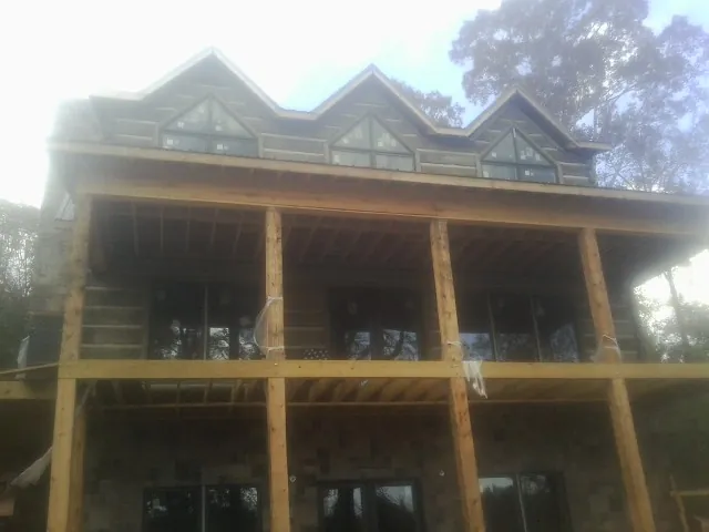 Dormers and porch framing on a large log home under construction — Roof Coating work by our crew in Sangerfield