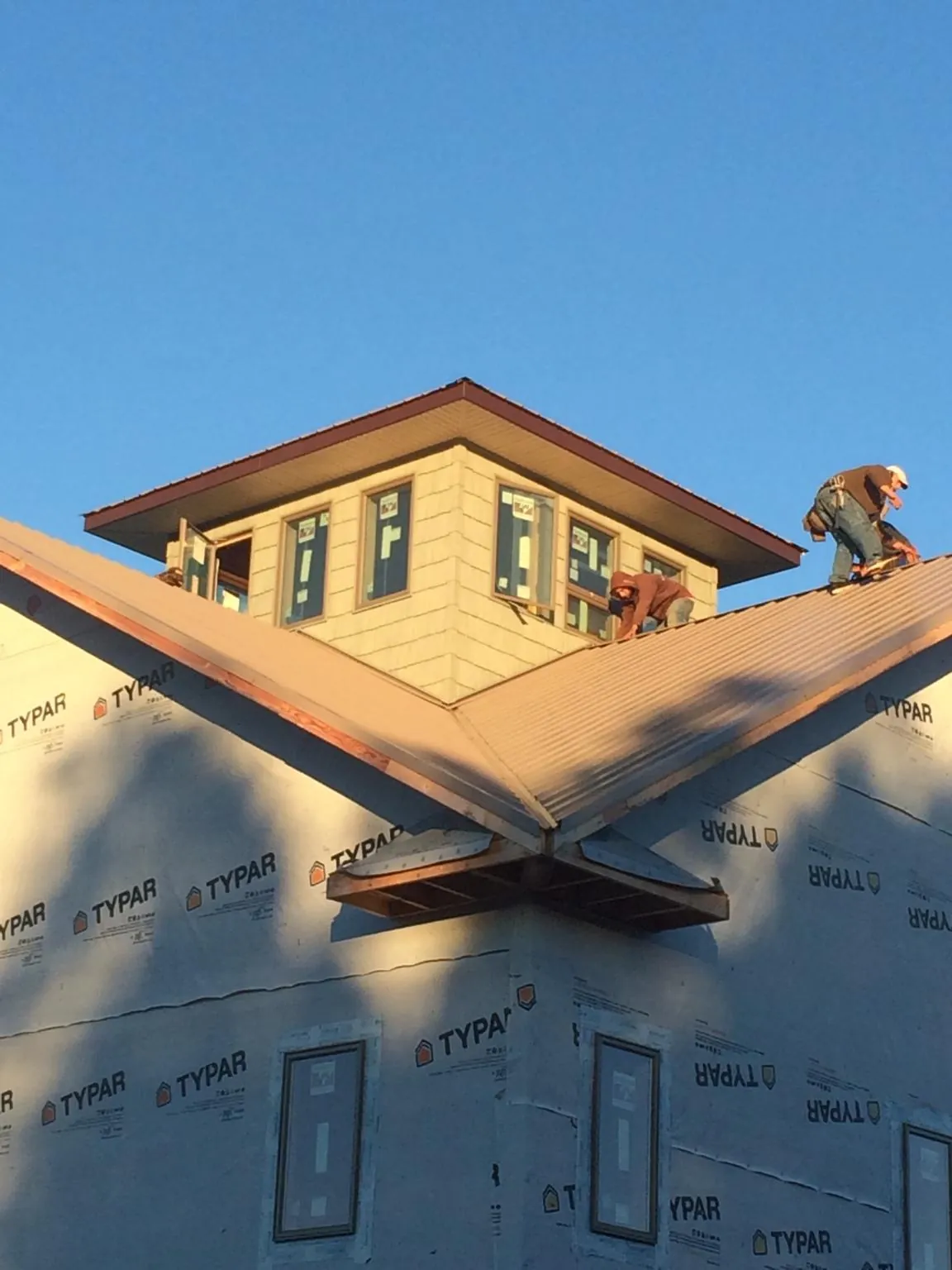 Roofers working around a rooftop cupola on a new metal roof at sunset — Roof Waterproofing in Sangerfield by Roofing Brothers